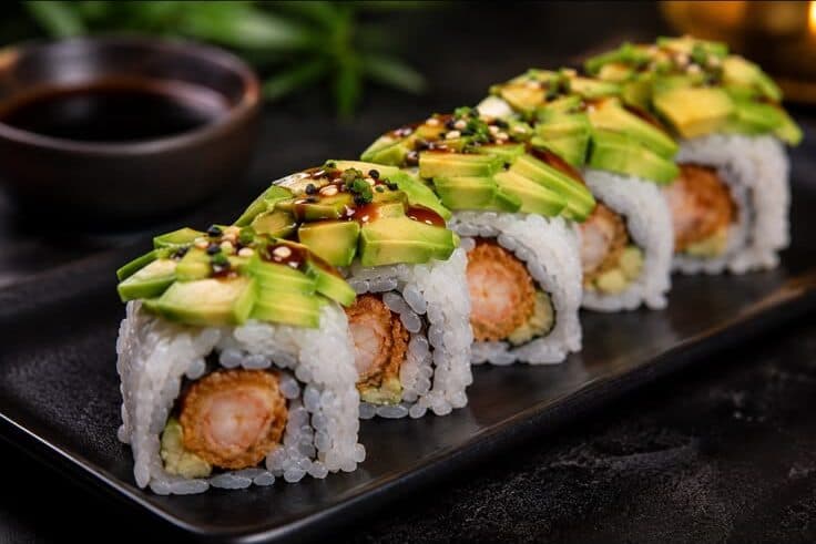 Dragon rolls à la crevette tempura recouverts de lamelles d'avocat et de sauce teriyaki