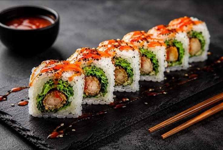 Rangée de makis uramaki garnis d'avocat, crevettes et œufs de poisson, nappés de sauce