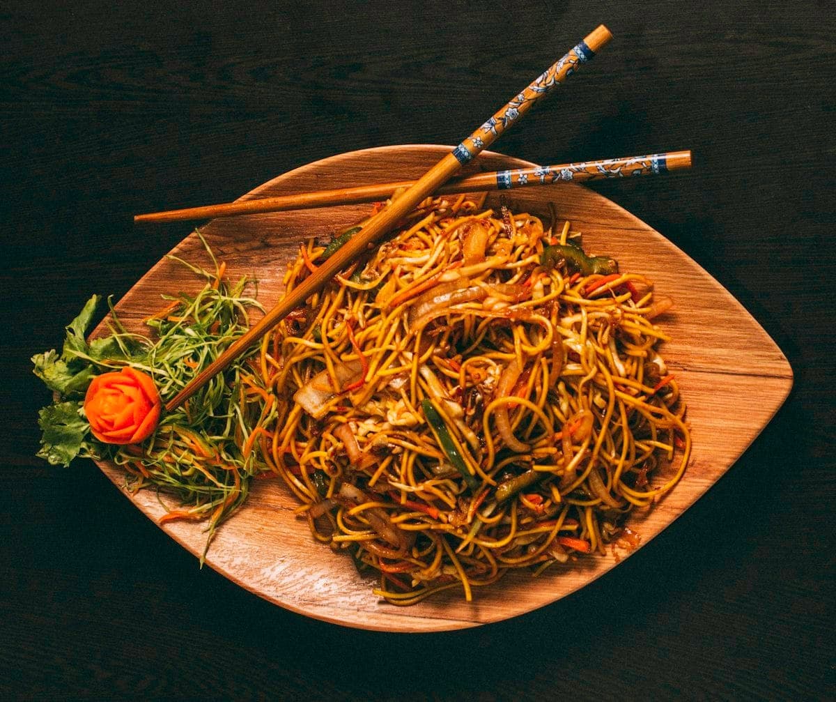Nouilles sautées asiatiques aux légumes servies sur planche en bois